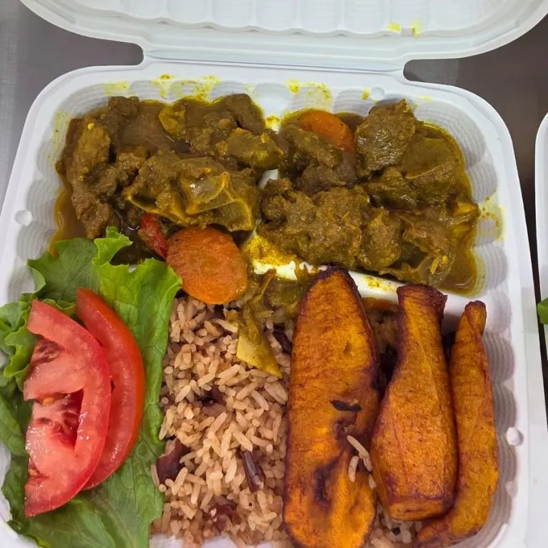 Curry goat with rice and peas and fried plantain